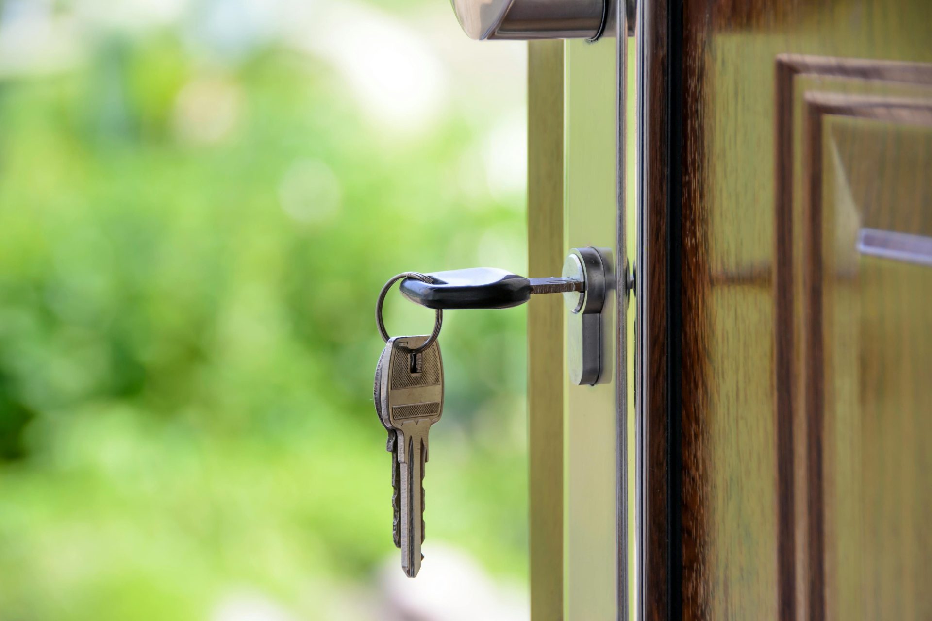 Llave insertada en la cerradura de la puerta sobre un fondo verde difuminado, que simboliza la seguridad y el sector inmobiliario.