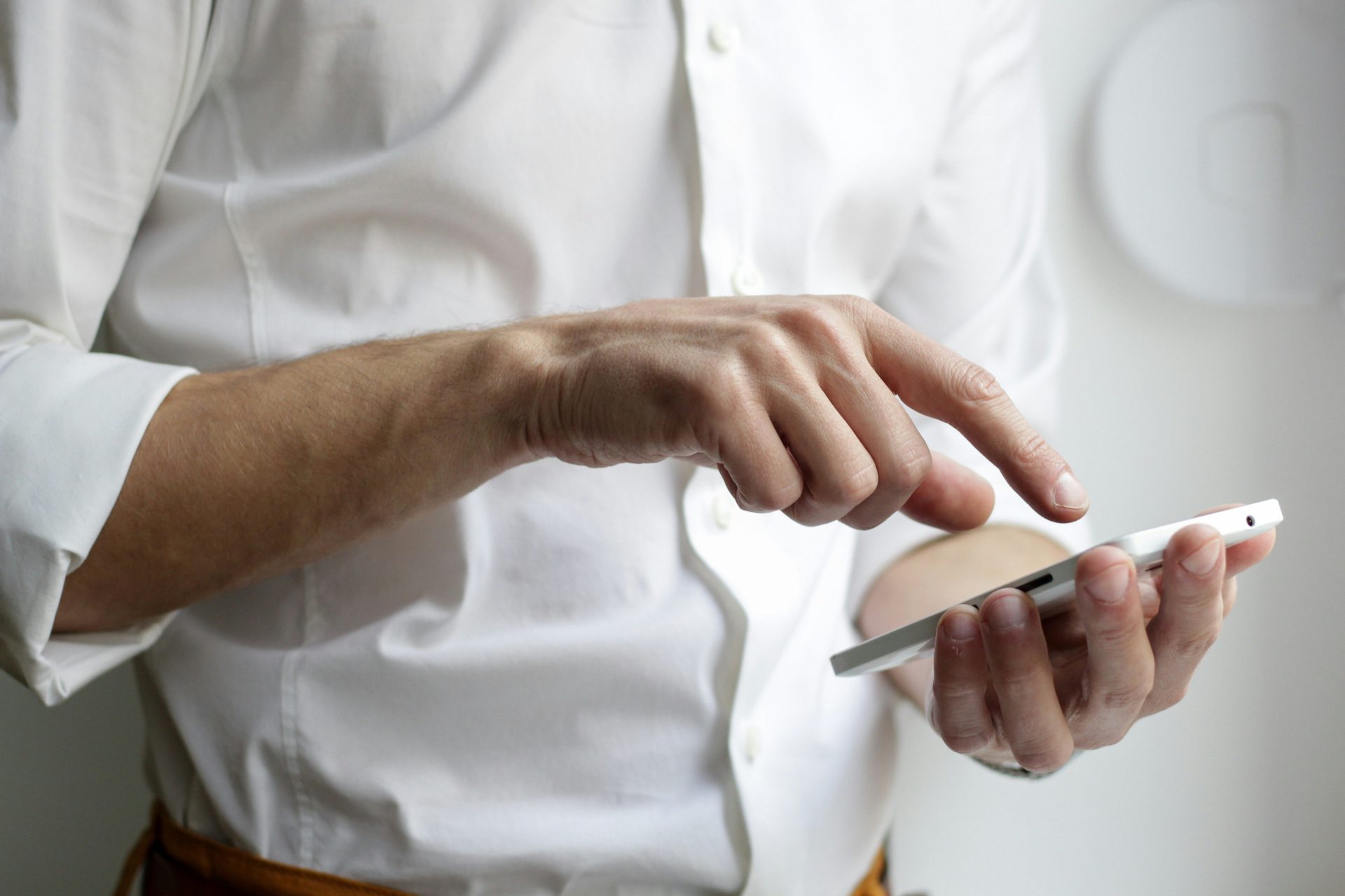 Persona con un teléfono inteligente Android blanco y camisa blanca.